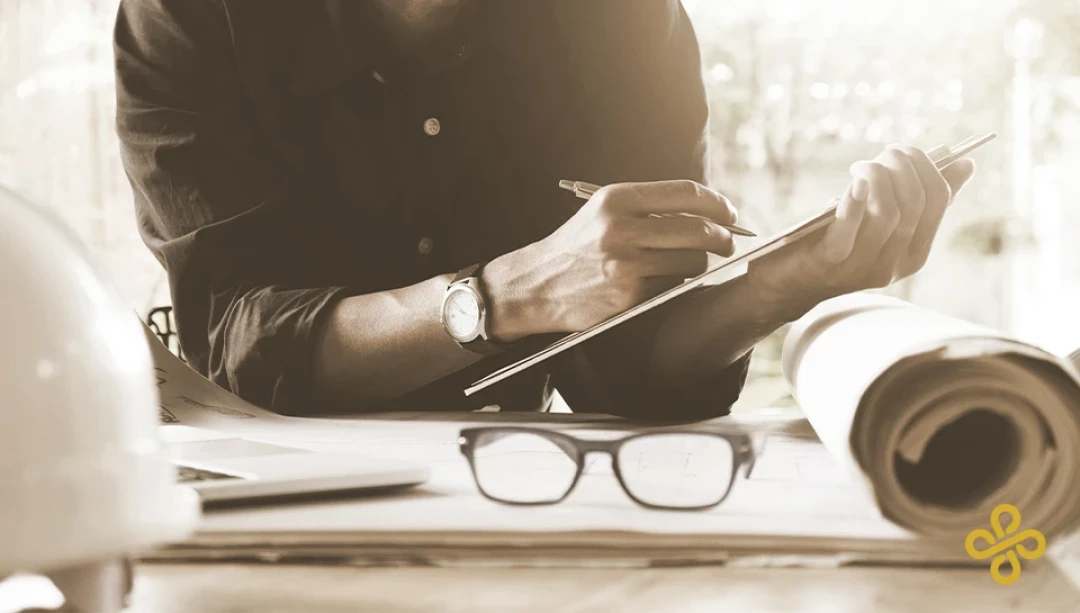 A man sat holding a clipboard working at desk