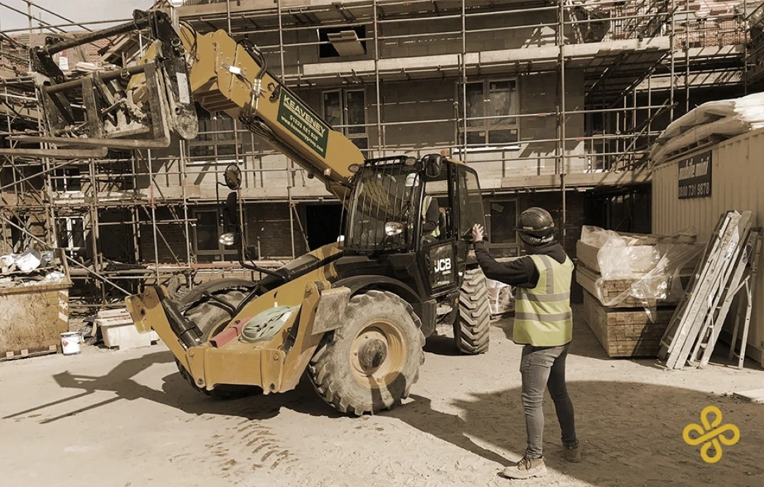 A vehicle banksman directing a yellow excavator