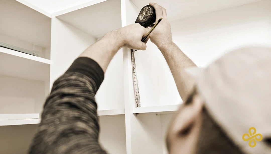 A tradesman using a tape measure on a cupboard