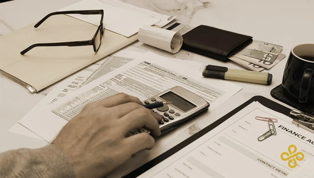 A close-up shot of a hand using a calculator that's laid on top of paperwork